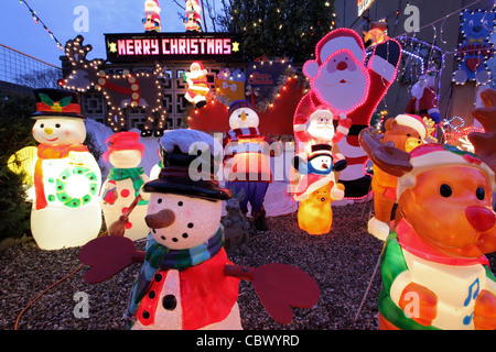 Glühende beleuchtet bunt Kunststoff Kitsch Weihnachtsschmuck im Garten s UK Doppelhaushälfte, Suffolk, England Stockfoto
