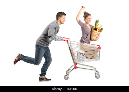 Person aufgebracht eine glückliche Frau in einem Einkaufswagen mit Papiertüte voll mit Essen Stockfoto