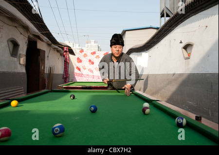 Xiadian, Beijing. Mann spielen Pool in einem Armenviertel mit in den Hintergrund Beijing Central Business District. Stockfoto