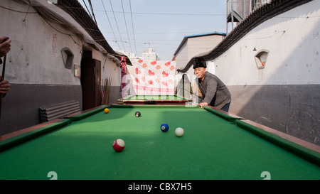 Xiadian, Beijing. Mann spielen Pool in einem Armenviertel mit in den Hintergrund Beijing Central Business District. Stockfoto