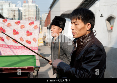 Xiadian, Beijing. Männer spielen Pool in einem Armenviertel mit in den Hintergrund Beijing Central Business District. Stockfoto