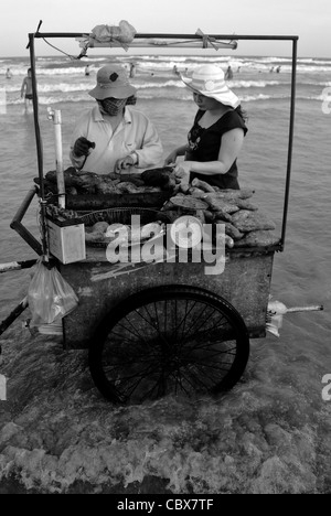 Vungtau, Vietnam. Anbieter verkaufen gegrillte Süßkartoffeln am Strand. Stockfoto