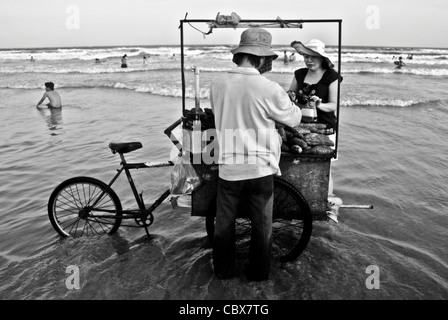 Vungtau, Vietnam. Anbieter verkaufen gegrillte Süßkartoffeln am Strand. Stockfoto