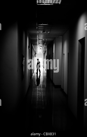 Chaoyang, Beijing. Security Guard zu Fuß durch einen Korridor in einem Bürogebäude. Stockfoto