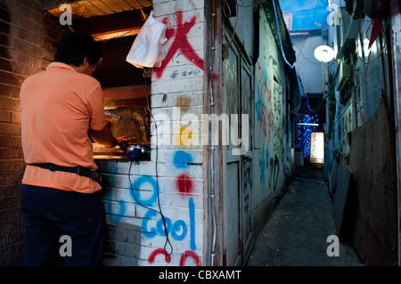 Beijing, Gulou Bereich. Mann bereitet Lamm Kebab auf der Straße. Stockfoto