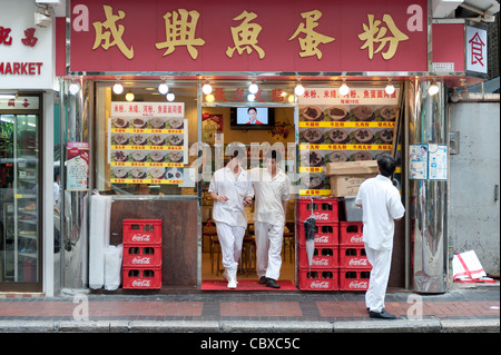 Kowloon, Hong Kong. Männer gehen aus einem Restaurant nach dem Mittagessen. Stockfoto