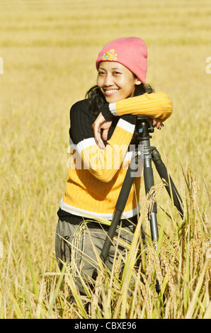 Frau, stützte sich auf einem Stativ stehend in einem Reisfeld bereit für die Ernte, Thailand, Asien Stockfoto