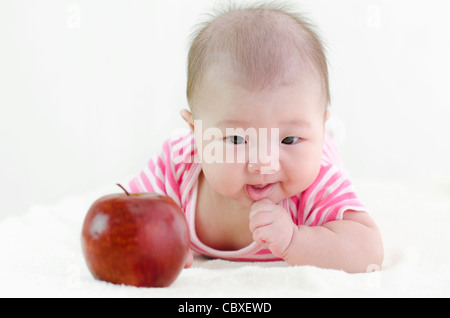 Asiatische Mädchen versuchen, schnappen Sie sich einen großen Apfel, konzentrieren sich auf baby Stockfoto