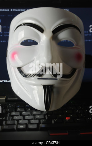 Maske von der Hacker-Gruppe "Anonymous" liegen auf einer Computertastatur Stockfoto