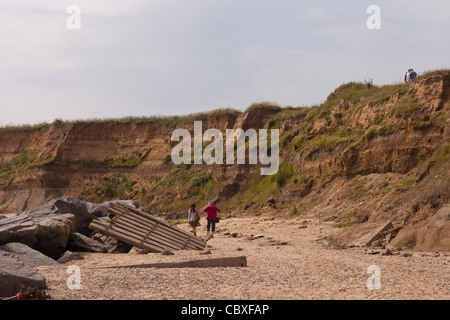 Happisburgh Küste, North Norfolk, East Anglia. Erosion der Felsen an der Nordsee; Menschen unter den zerstörten Küstenschutzes. Stockfoto