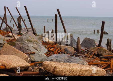 Happisburgh Beach, North Norfolk. Überbleibsel aus Metall Brakewaters durch Kraft der ankommenden Gezeiten zerstört. Rock und konkrete Blöcke. Stockfoto