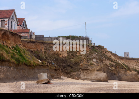 Happisburgh Küste, North Norfolk, East Anglia. Erosion der Felsen an der Nordsee;  Wohnungen. Turm der Kirche über Klippe Stockfoto