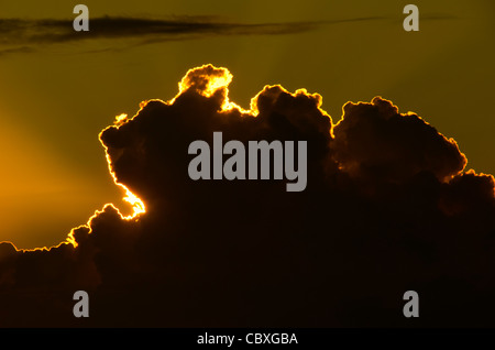 US JUNGFERNINSELN, USA – die untergehende Sonne beleuchtet den scharf definierten Rand einer Wolke mit goldenem Licht und erzeugt einen dramatischen Himmel über den karibischen Gewässern der US Jungferninseln. Stockfoto