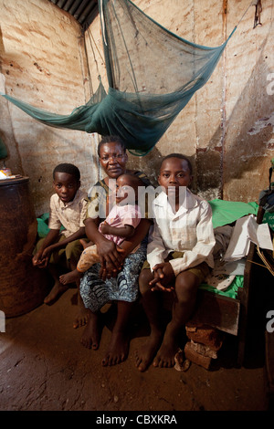 Eine Familie sitzt in ihrem kleinen ein-Zimmer-Haus in Morogoro, Tansania, Ostafrika. Stockfoto