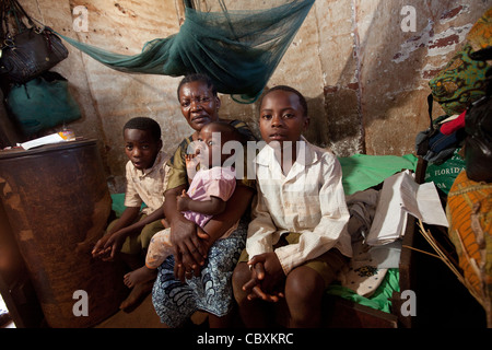 Eine Familie sitzt in ihrem kleinen ein-Zimmer-Haus in Morogoro, Tansania, Ostafrika. Stockfoto