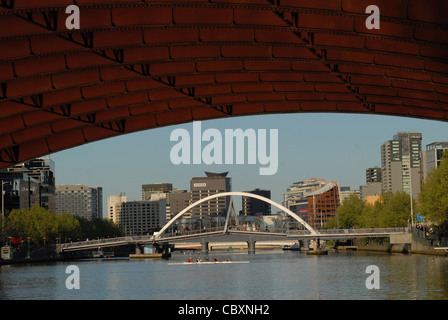 Blick von St. Kilda Road Bridge auf dem Yarra River Southbank (li.) und CBD (r) durch eine Fußgängerbrücke in Melbourne, Victoria verbunden Stockfoto