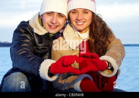 Porträt des glücklichen Paares in warme Kleidung, Hände, Herz indem Stockfoto