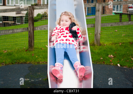3 Jahre altes Kind Mädchen Kleinkind Kleinkind spielen Sliding Down A Slide In A Kinderspielplatz Stockfoto