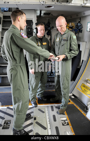 US Air Force Tech. Sgt. Chris Copans (von links), Staff Sgt. Todd Perkins und der schwedische 1. LT. Harry Johansson, C-17 Globemaster III, die dem Schwerlastflügel auf der Pápa Air Base, Ungarn, zugewiesen wurden, gehen vor dem Abflug von Ramstein Air Base, Deutschland, eine Checkliste für die Vorfahrt vom 18. August durch. Die HAW, die aus 12 Nationen besteht, arbeitet unabhängig vom militärischen Kommando der NATO und wurde geschaffen, um Nationen dabei zu helfen, globale REACH-Verpflichtungen zu erfüllen. Stockfoto