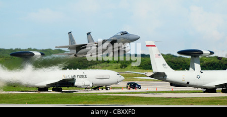 Ein F-15 Adler hebt von der Andersen Air Force Base, Guam, an der Fluglinie ab, während zwei E-3 Sentries im Hintergrund zu sehen sind, während sie an der Valiant Shield 2010 Übung 16. September 2010 teilnehmen. Stockfoto