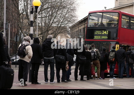 eine Schlange von Menschen warten auf einen roten Londoner Bus an Bord Stockfoto