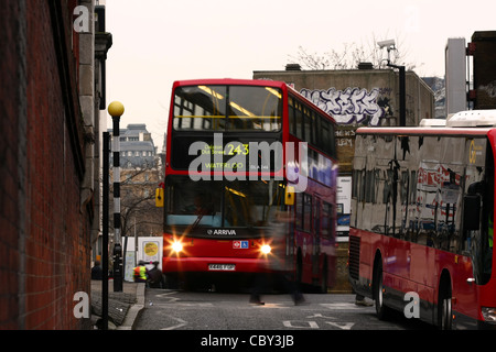 verschwommene Umrisse einer Person, die einen Zebrastreifen überqueren, zwischen zwei roten Londoner Busse bei Waterloo, London Stockfoto