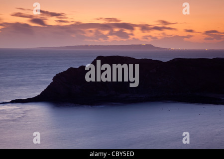 Ein Blick über Lulworth Cove Dorset auf der Isle of Portland bei Sonnenuntergang mit den Lichtern von Weymouth Glühen Stockfoto