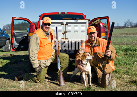 Zwei Upland Vogel Jäger posiert hinter LKW mit Schrotflinten, Wachteln und English Setter Stockfoto