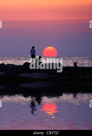 Zwei Frauen auf Wellenbrecher Silhouette gegen See Michigan Sonnenuntergang in Holland, Michigan, USA Stockfoto