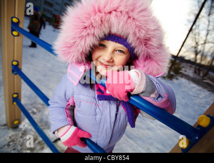 Glückliches Mädchen in Winterwear Blick in die Kamera beim Spielen im freien Stockfoto