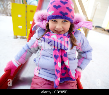 Glückliches Mädchen in Winterwear Blick in die Kamera beim Spielen im freien Stockfoto