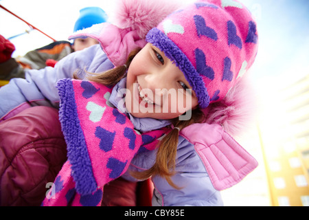 Glückliches Mädchen in Winterwear Spaß außerhalb mit ihrer Freundin im Hintergrund Stockfoto