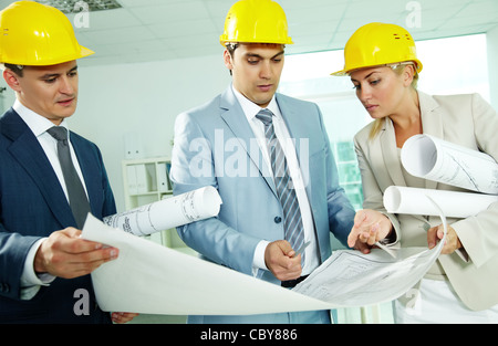 Porträt von drei Architekten in Helme diskutieren Blaupause Stockfoto