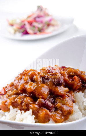 Chili con Carne mit Basmati-Reis und etwas Salat im Hintergrund Stockfoto