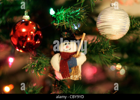 Weihnachtsbaum Dekoration Schneemann roten Schal, schwarzen Hut, Besen auf grün künstlicher Baum, helle rote Christbaumkugel, gestreift Silber Kugel Stockfoto