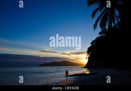 Frau zu Fuß am Strand in Costa Rica bei Sonnenuntergang mit Palmen Stockfoto