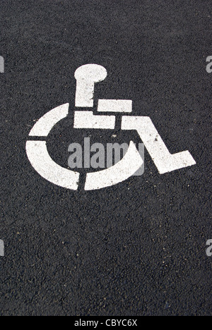 Ein weißer Handicap Parken Symbol ist auf einem schwarzen Pflaster gemalt. Stockfoto