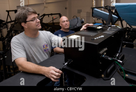 Brian Miller, L3 Communications Assistant Site Supervisor, Und Brian Smith, der leitende Techniker, überprüfen die Funktionen eines Projektors aus dem F-16 Fighting Falcon Mission Training Center Flugsimulator 13. Juni 2011, während der Installationsprohase auf der Nellis Air Force Base, Nev. Der Simulator wird F-16 Piloten ermöglichen, Flugmanöver, Formationen, Und Luft-Luft-Kampf mit einer 360-Grad-Ansicht. Dieser Simulator ist einer von vier, die auf der Nellis AFB gebaut werden. Stockfoto