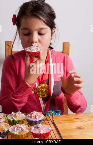 Junges Mädchen essen Muffins allein. Stockfoto