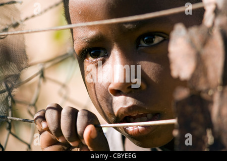 Afrikanischen jungen suchen durch Draht Zaun - Twyfelfontein - Damaraland, Namibia, Afrika Stockfoto