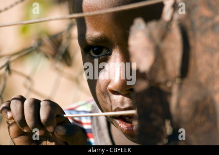 Afrikanischen jungen suchen durch Draht Zaun - Twyfelfontein - Damaraland, Namibia, Afrika Stockfoto