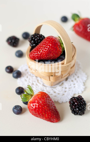 Erdbeeren, Brombeeren und Heidelbeeren in einem Korb auf einer Deckchens Stockfoto