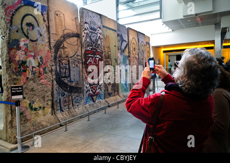 Touristen nutzen eine Smartphone und ein Foto von dem großen Teil der Berliner Mauer an der Newseum in Washington DC. Das Newseum ist ein 7-geschossige, privat finanzierte Museum, Journalismus und News. Es öffnete am heutigen Standort an der Pennsylvania Avenue im April 2008. Stockfoto