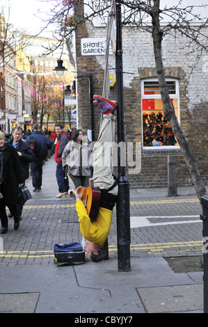 Covent Garden Street Performer kopfüber aus einem Laternenpfahl, London. Stockfoto