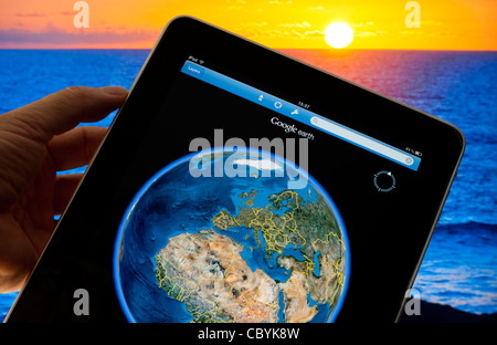 Apple iPad Smart Tablet mit Google Earth Streaming-Anwendung 4g auf dem Bildschirm mit Weltkugel, mit Großbritannien Frankreich Afrika etc, Sonnenuntergang im Hintergrund Stockfoto