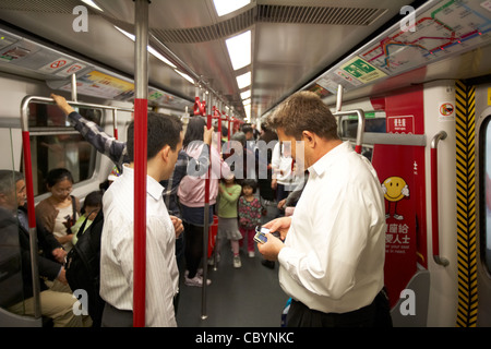 westliche Geschäftsleute mit Mobiltelefonen in Zug Beförderung auf Hong Kong Mtr öffentlichen transport System Sonderverwaltungsregion Hongkong China Asien Stockfoto