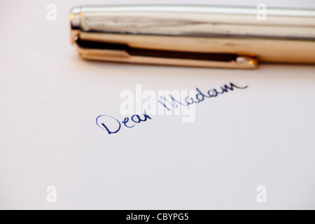 die Worte "Sehr geehrte Frau" handschriftlich mit Tinte mit Füllfederhalter im Hintergrund Stockfoto