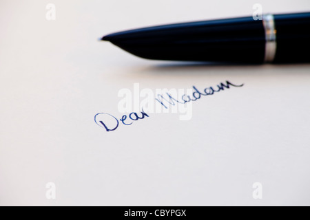 die Worte "Sehr geehrte Frau" handschriftlich mit Tinte mit Füllfederhalter im Hintergrund Stockfoto