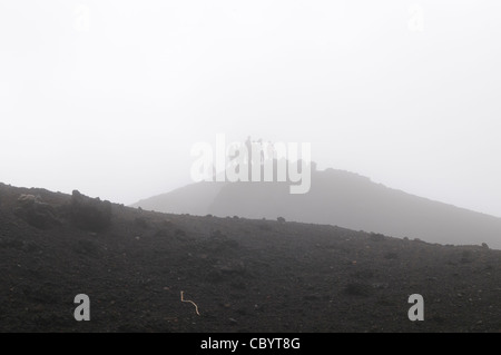 VULKAN PACAYA, Guatemala – Eine Gruppe von Touristen steht auf einem der Ausläufer auf dem Gipfel des Vulkans Pacaya und wird teilweise von der Mischung aus Wolken und Dampf umhüllt. Pacaya ist ein aktiver Vulkan, der Teil des Zentralamerikas Vulkanbogens ist. Es ist ein beliebtes Touristenziel, das von Antigua und Guatemala City aus leicht zu erreichen ist. Es liegt im Pacaya-Nationalpark und erhebt sich auf 2.552 Meter (8.373 ft). Die letzte größere Eruption, die erhebliche Schäden an den umliegenden Dörfern verursachte und den Gipfel neu formte, fand im Mai 2010 statt. Die Eruption und die verstreute vulkanische Asche über den größten Teil der Stockfoto