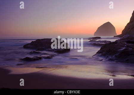 Oregon Rocky Beach bei Sonnenuntergang mit Haystack Rock in der Ferne Stockfoto